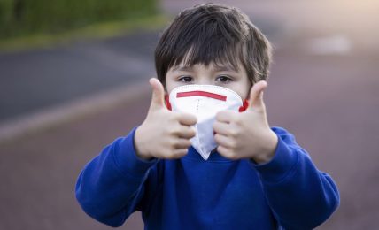 Niño con mascarilla hace el signo de todo ok con los pulgares hacia arriba